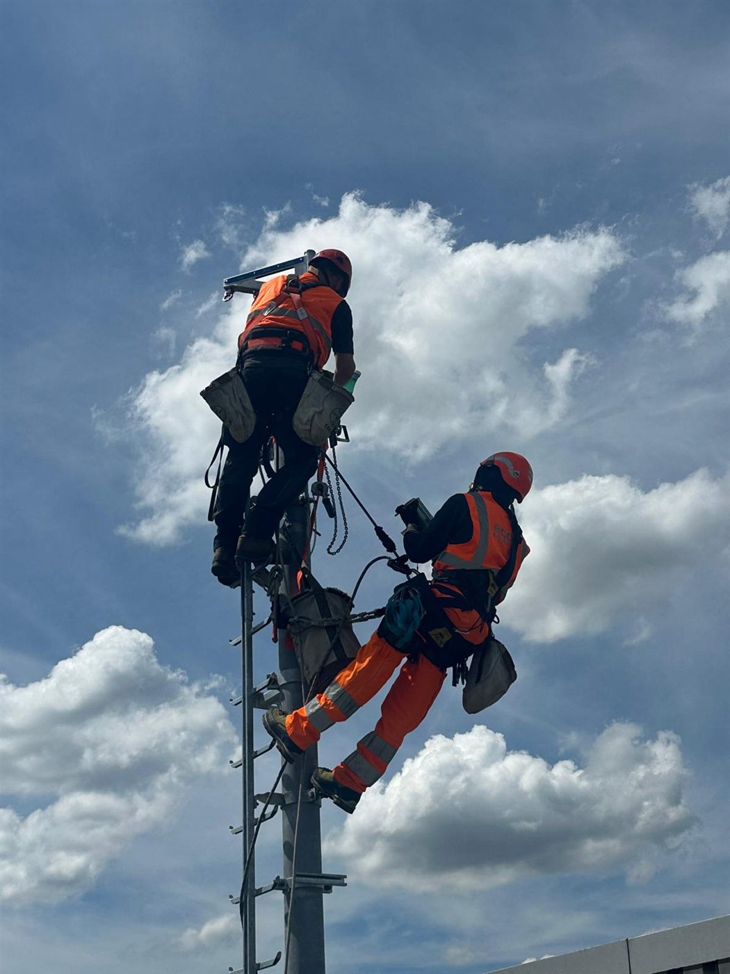 Zwei gesicherte Techniker an einem Mast
